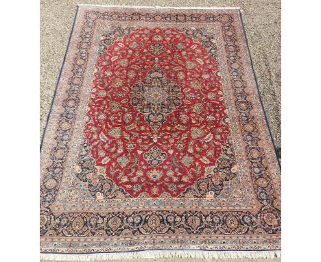 A hand knotted Persian Kashan carpet, the red fields with central turquoise pendant, with foliate palmettos and a navy multi 