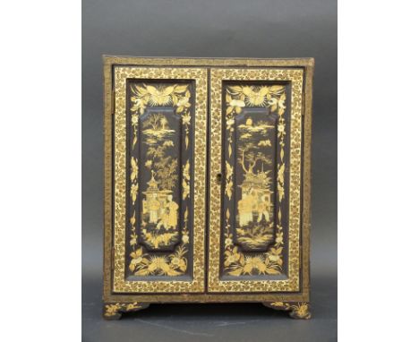 A Japanese lacquer cabinet all over decorated in gilt with figures, buildings and insects, the two doors opening to reveal fi