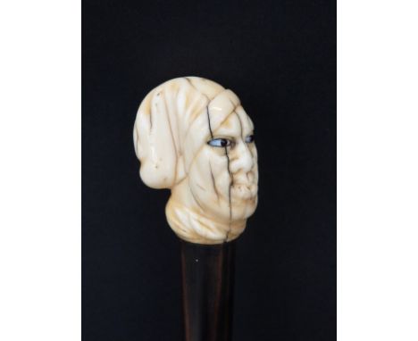 A 19thC swordstick handle with carved marine ivory finial in the form of a man's head with glass inset eyes, rosewood handle 