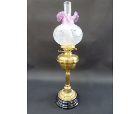 A brass oil lamp with engraved pink frilled glass shade, 75cm tall