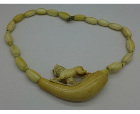 An ivory bead necklace decorated with a carved meerschaum pipe mounted with a lion