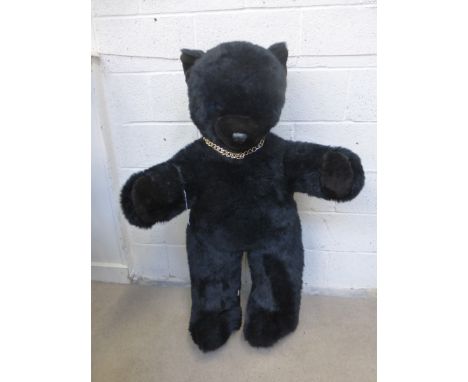 A large floor standing black teddy bear with out reached arms and blue glass eyes, 48 inches tall.