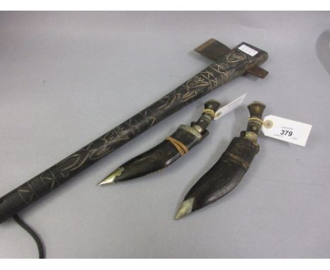 Two small horn handled leather sheathed kukris and an axe with incised handle decorated with figures 