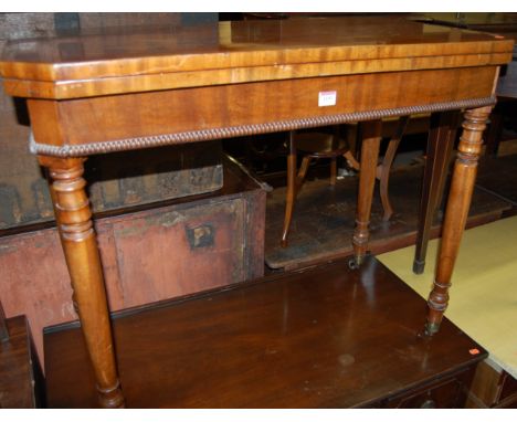 An early Victorian mahogany fold-over card table, having typical revolving action, beaded edge, canted corners, and on turned