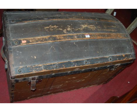An early 20th century canvas clad wooden and metal bound hinge dome top travelling trunk, having leather end carry handles an