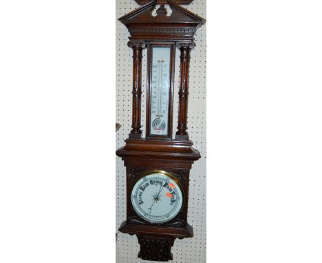 An early 20th century carved oak aneroid two-dial wheel barometer, having Ionic capped and fluted columns 