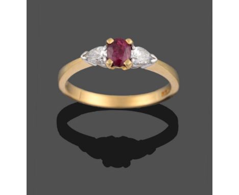 An 18 Carat Gold Ruby and Diamond Three Stone Ring, a cushion cut ruby in yellow claws sits between two pear cut diamonds in 