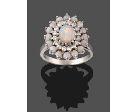 An 18 Carat White Gold Opal and Diamond Cluster Ring, an oval cabochon opal within a border of round brilliant cut diamonds, 