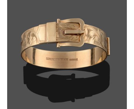 A 9 Carat Gold Hinged Bangle, by Bracelon Ltd, in the form of a belt buckle with floral motif engraving throughout, measures 