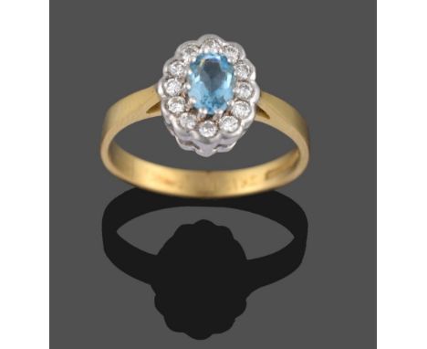 An 18 Carat Gold Aquamarine and Diamond Cluster Ring, the oval cut aquamarine in white claws sits above a border of round bri
