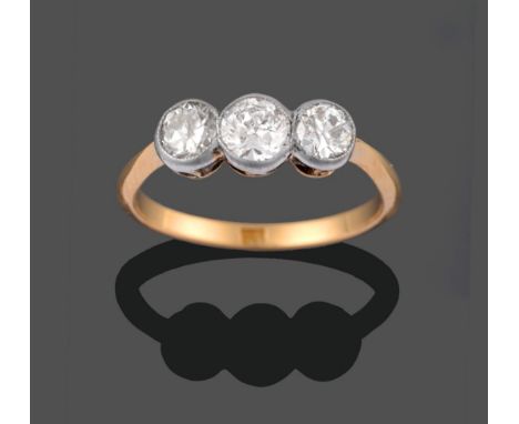 A Diamond Three Stone Ring, the graduated old cut diamonds in white millegrain settings to yellow tapered shoulders and a pla