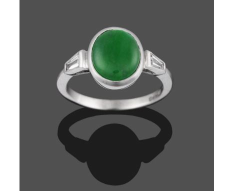 An 18 Carat White Gold Jade and Diamond Ring, the oval cabochon jade in a white collet setting with a tapered baguette cut di