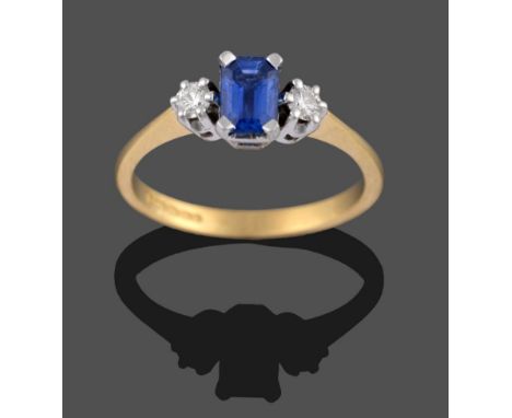 An 18 Carat Gold Sapphire and Diamond Three Stone Ring, the emerald-cut sapphire in a white four claw setting set between two