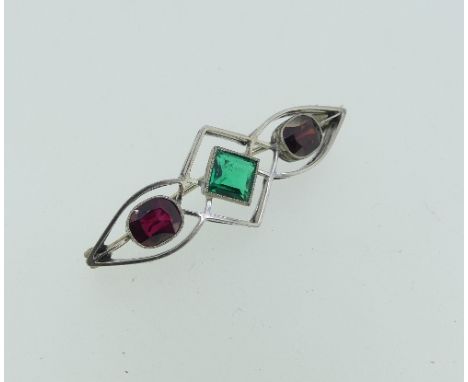 An attractive Brooch, formed of an open framework with a central millegrain set emerald, an oval millegrain set garnet on one