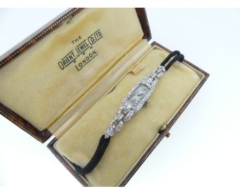 A diamond set platinum lady's Cocktail Wristwatch, with enamel dial with black Arabic Numerals, black cord strap with replace