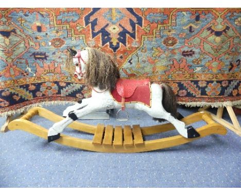 A Painted Wood Rocking Horse on Bow Rockers, with brown horse haired tail and mane, red leather saddle and reigns, length 56i