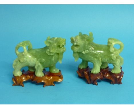 A pair of Chinese smoke green and grey Figures of Kylins, carved with winged legs, triple scroll tail and bearded lower jaw, 