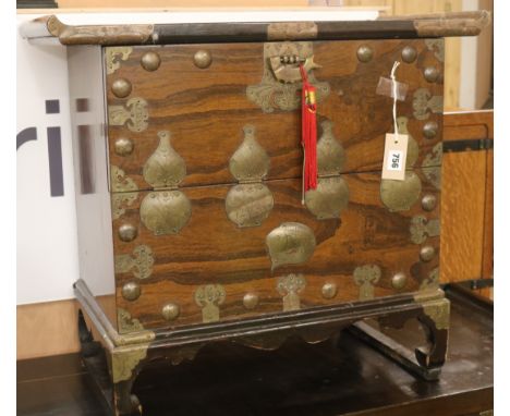 A Korean brass-mounted carved hardwood tansu, having curved moulded top over a shallow upper compartment fitted a pair of hin