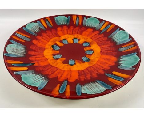 A vibrant large POOLE POTTERY charger in shades of volcanic orange, scarlet and teal, 41cm diameter crack to base but not rea