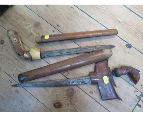 An Indonesian hardwood kris dagger, with grain effect blade and horn terminal to the scabbard, length of blade 34cm and anoth