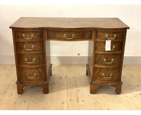 A Georgian style figured walnut serpentine knee hole desk, first half of the 20th century, with cross banded top over one lon