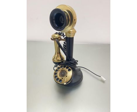 A modern reproduction brass and black composition candlestick style telephone with numerical dial, fitted for a modern phone 