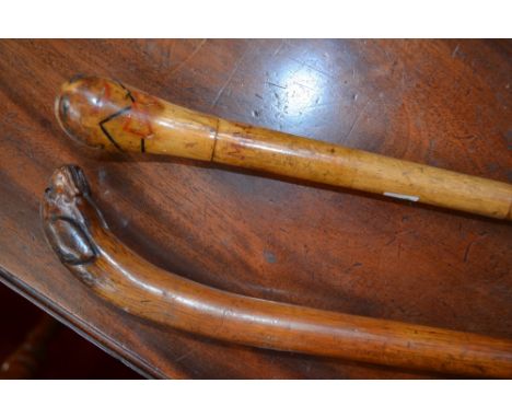 A 19th century novelty walking cane, the pommel carved as the head of a dog; another, painted as a comical man, wearing a bow