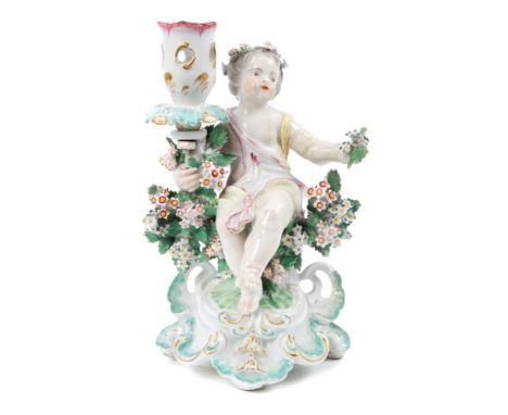 Late 18th century Derby porcelain candlestick with seated putto with flowers and bocage with loop handle to rear, on rococo s