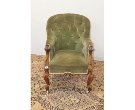 Victorian walnut spoon back easy chair with green button upholstery, on carved cabriole legs and castors
