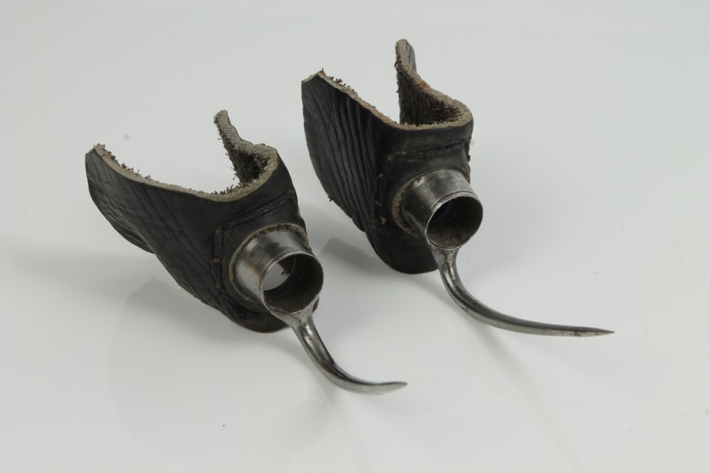 Pair of antique steel cockfighting spurs on leather mounts