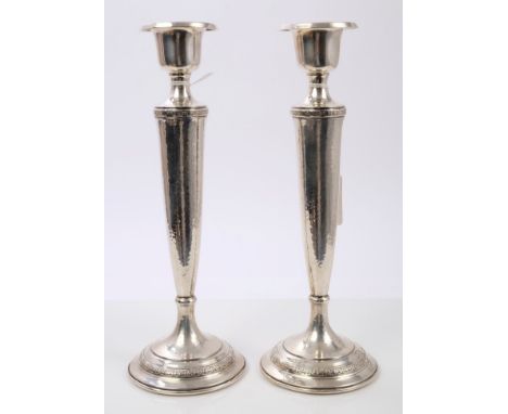 Pair early 20th century American silver candlesticks of tapering form, with spot-hammered finish and flower-head and bow deco