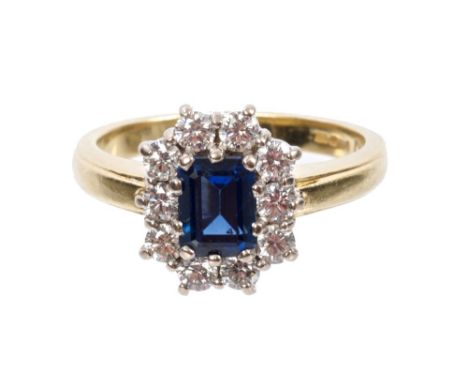 Sapphire and diamond cluster ring with a rectangular step cut blue sapphire measuring approximately 6.00mm x 4.75mm x 3.50mm,