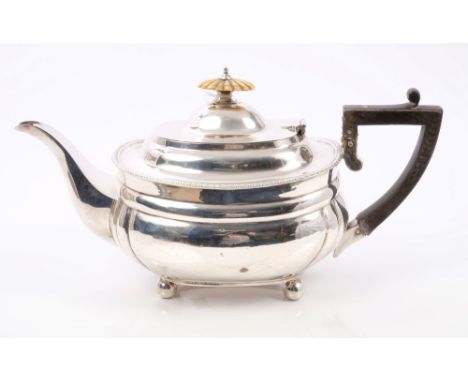 George V silver teapot of compressed baluster form, with fluted panels and gadrooned border, angular ebony handle, hinged dom