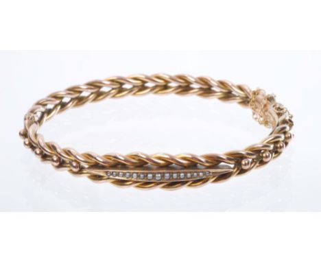 Victorian yellow metal hinged bangle with a row of graduated seed pearls on a ropetwist band, stamped '9ct' CONDITION REPORT 