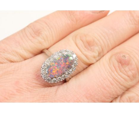 Black opal and diamond cluster ring, the oval cabochon opal of approx. 13mm x 6mm, bordered with small brilliants in a steppe