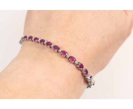 Ruby and diamond line bracelet, in 18ct white gold, set with 30 oval cut rubies totalling approx. 7.36cts, dispersed with tin