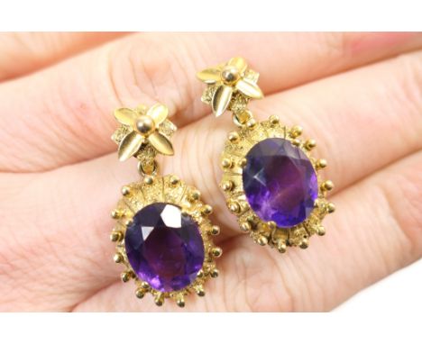 Pair of 9ct gold and amethyst pendant earrings, oval cut amethyst 11mm x 9mm, in a studded yellow gold oval mount suspended f