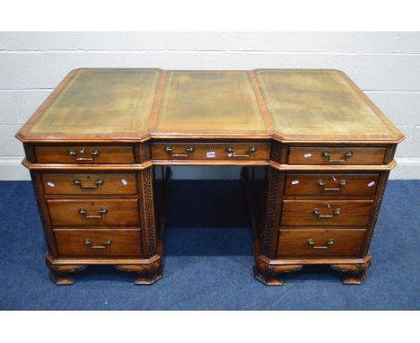 A REPRODUCTION MAHOGANY PARTNERS DESK, the top with canted corners above fretwork decoration, inverted breakfronts to front a