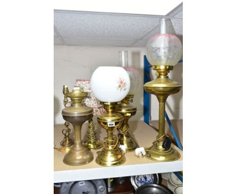 A GROUP OF SIX BRASS TABLE LAMPS, including three converted to electric oil lamps, with glass shades, a double burner oil lam