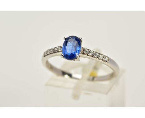 A 9CT WHITE GOLD RING, designed with a claw set oval blue stone, assessed as Kyanite, circular cut colourless topaz detailed 