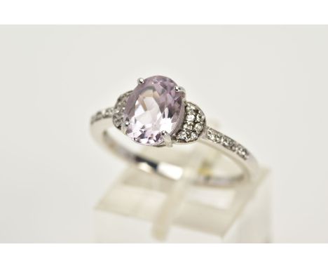 A 9CT WHITE GOLD AMETHYST RING, designed with a claw set, oval cut pale amethyst, flanked with colourless stone set shoulders