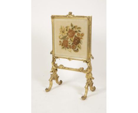 A ROCOCO STYLE GILTWOOD AND GESSO FIRE SCREEN with a rectangular floral wool work panel, on ornate acanthus and shell moulded
