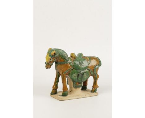 A CHINESE "TILE WORKS" FIGURE OF A HORSE wearing an elaborate saddle covered in straw and green-coloured glazes, on a rectang