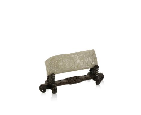 A CHINESE WHITE JADE PLAQUE, carved with figures in a grotto amongst pine trees, bamboo and pagoda, on a wood stand, 29cms wi