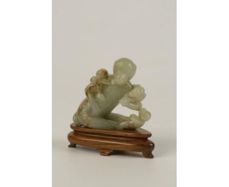 A CELADON AND RUSSET JADE 'MONKEY AND PEACH' GROUP, modelled as the seated monkey holding a peach with two playful young by i