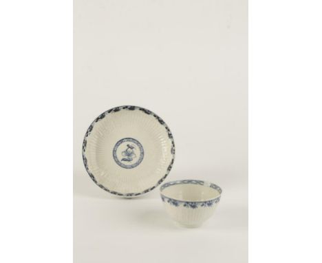 A FIRST PERIOD WORCESTER PORCELAIN TEA BOWL and saucer, the raised fluted and floral ground within borders of blue painted le
