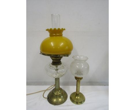 A converted oil lamp with amber coloured globe along with a candle lamp