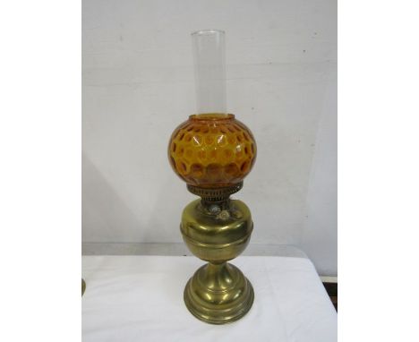 An oil lamp with amber coloured globe