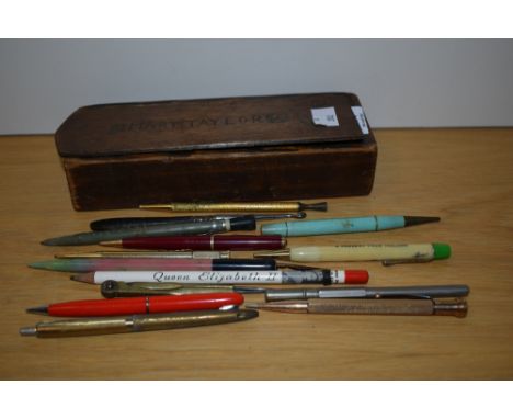 A 20th Century wooden sliding pencil box, measuring 21cm long, with vintage pens including a Parker Duofold fountain pen and 