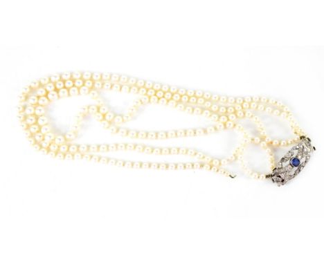A cased three-strand pearl necklace with white metal clasp set with blue spinel and diamonds, in the Art Deco style. CONDITIO